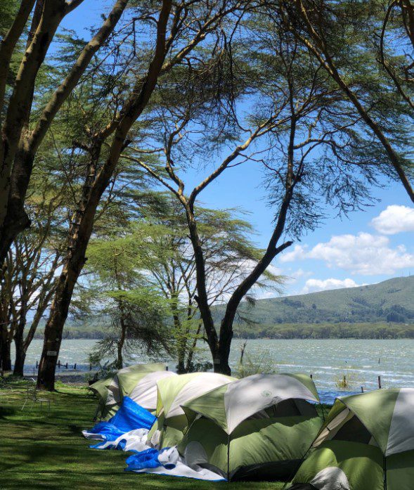 Lakeside view of fishing camps near Lake Naivasha with boats, tents, and scenic natural surroundings.